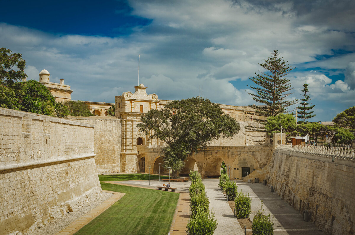 The historic stone entrance gate and landscaped moat of Mdina, next to Rabat